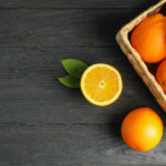 wicker basket with ripe oranges wooden table